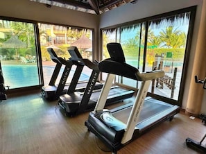 Un gimnasio con cintas de correr y vistas a un complejo turístico.