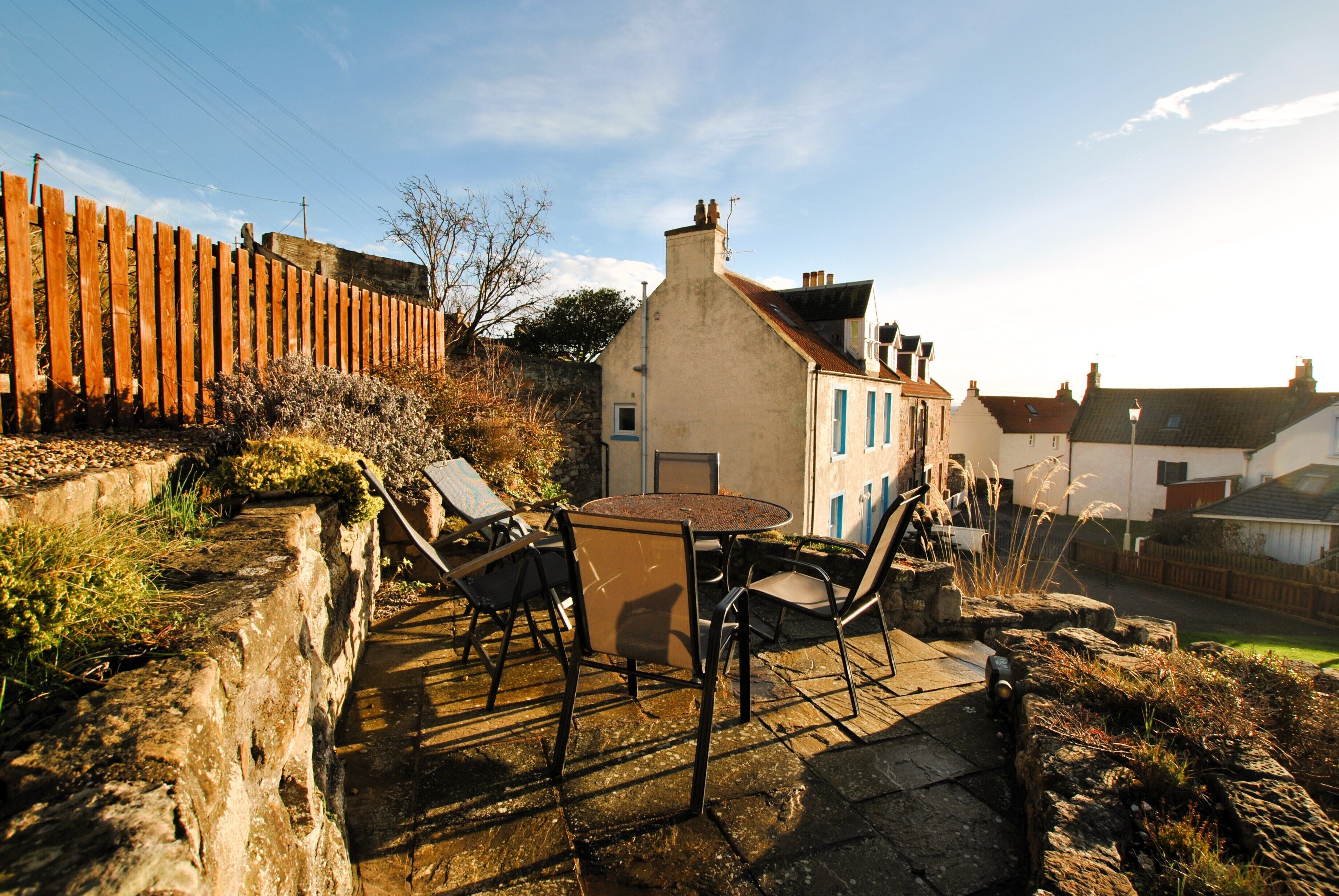 A patio with a table and chairs, a stone wall, and a wooden fence.