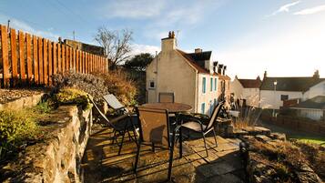 A patio with a table and chairs, a stone wall, and a wooden fence.