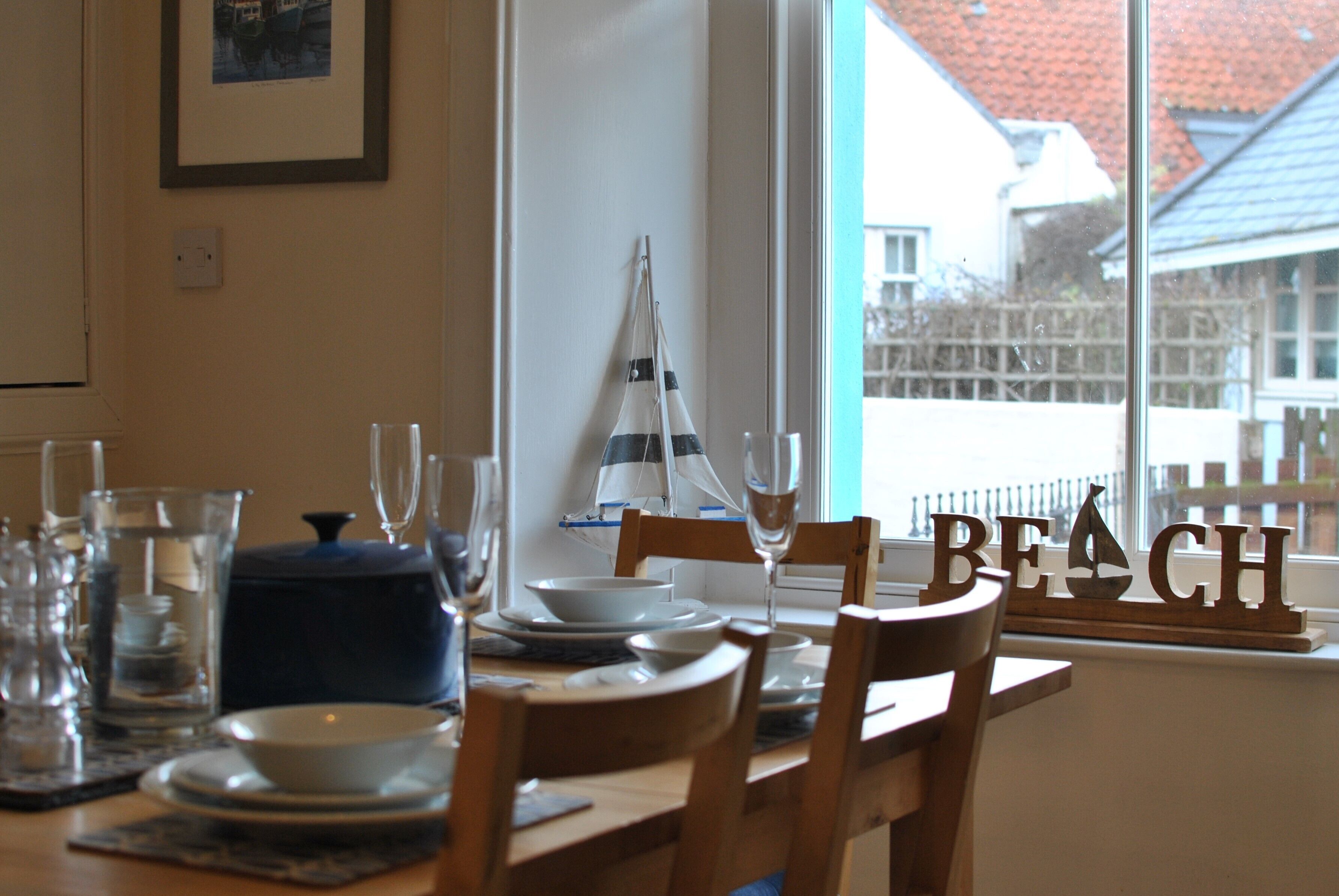 A dining table set with plates, glasses, and a decorative sailboat.