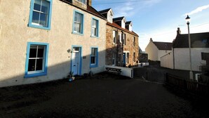 Eine enge Straße mit Gebäuden mit Steinverkleidungen und blauen Fensterrahmen.