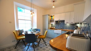 Una cocina moderna con una isla central, un comedor con sillas amarillas y baldosas de suelo estampadas.