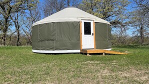 A large, green, dome-shaped tent with a white door and a small wooden platform at the entrance. - North Star Yurt at Whiterock Conservancy (Coon Rapids)