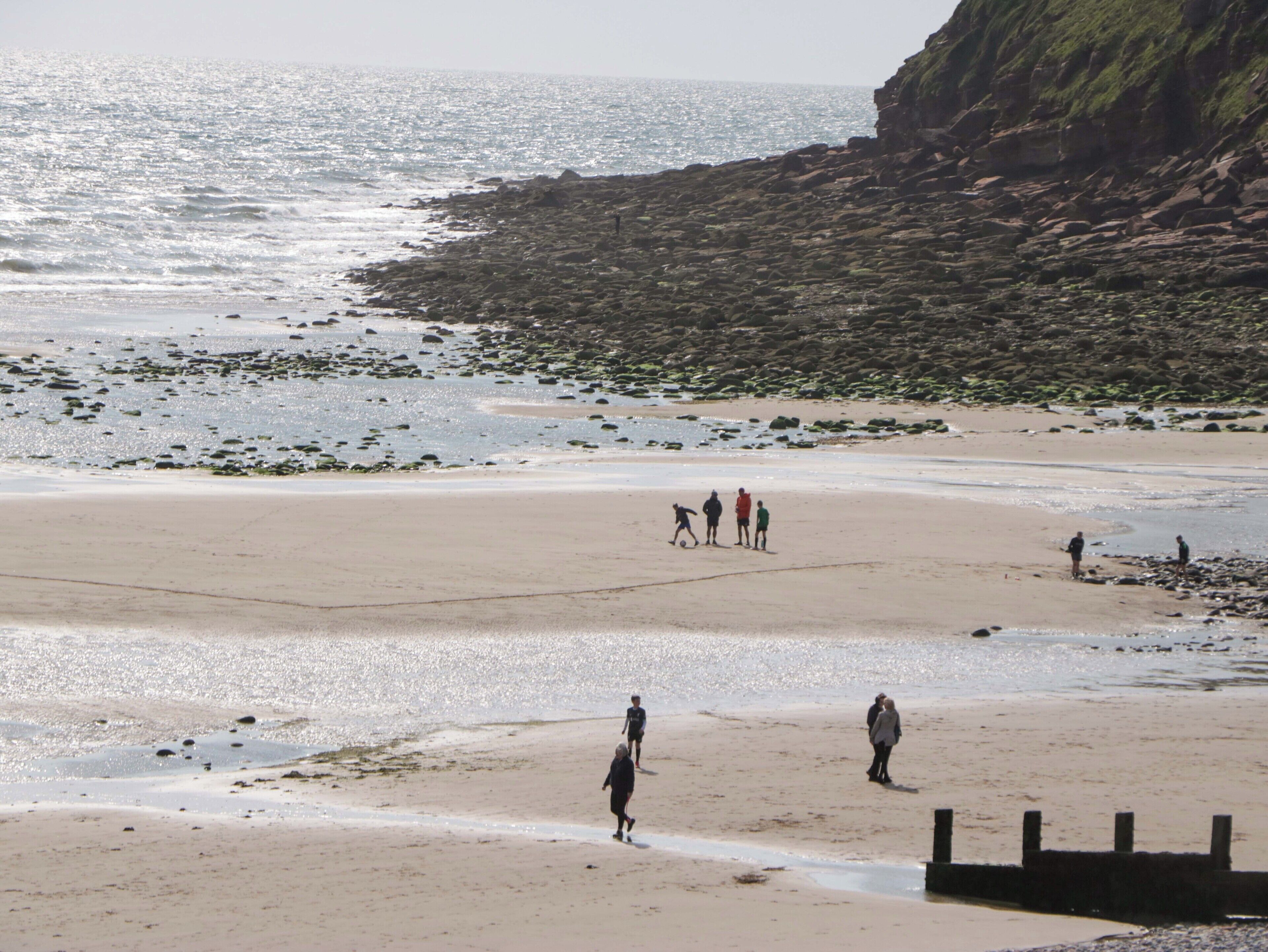 Een strand met rotsachtige kliffen en rustig water.