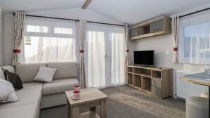 A modern living room with a sofa, a coffee table, a TV on a wooden stand, and a radiator. - Guillemot (St Bees)