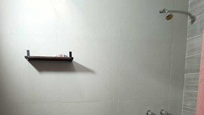 Un baño pequeño con inodoro, ducha y repisa sobre el inodoro.