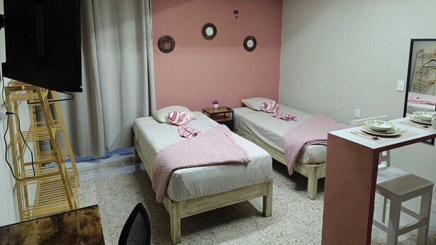 Una habitación con dos camas, un escritorio y una televisión.