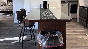 A modern kitchen with a central island, built-in appliances, and a dining area with a chair and table. - Gator Camp 2.7 off the rim of Lake Okeechobee Buckhead Ridge (Okeechobee)