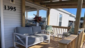 A covered porch with a white sofa and chairs, a wooden railing, and a number '1395' on the wall. - Gator Camp 2.7 off the rim of Lake Okeechobee Buckhead Ridge (Okeechobee)