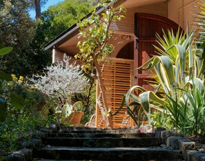 A garden with a wooden staircase leading to a house with a brown door and a wooden fence. - Sandra and Lucia's Home in an Oasis of Peace (Quercianella)