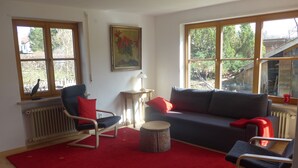 Un salon avec une moquette rouge, un canapé bleu, une chaise en bois et une table.