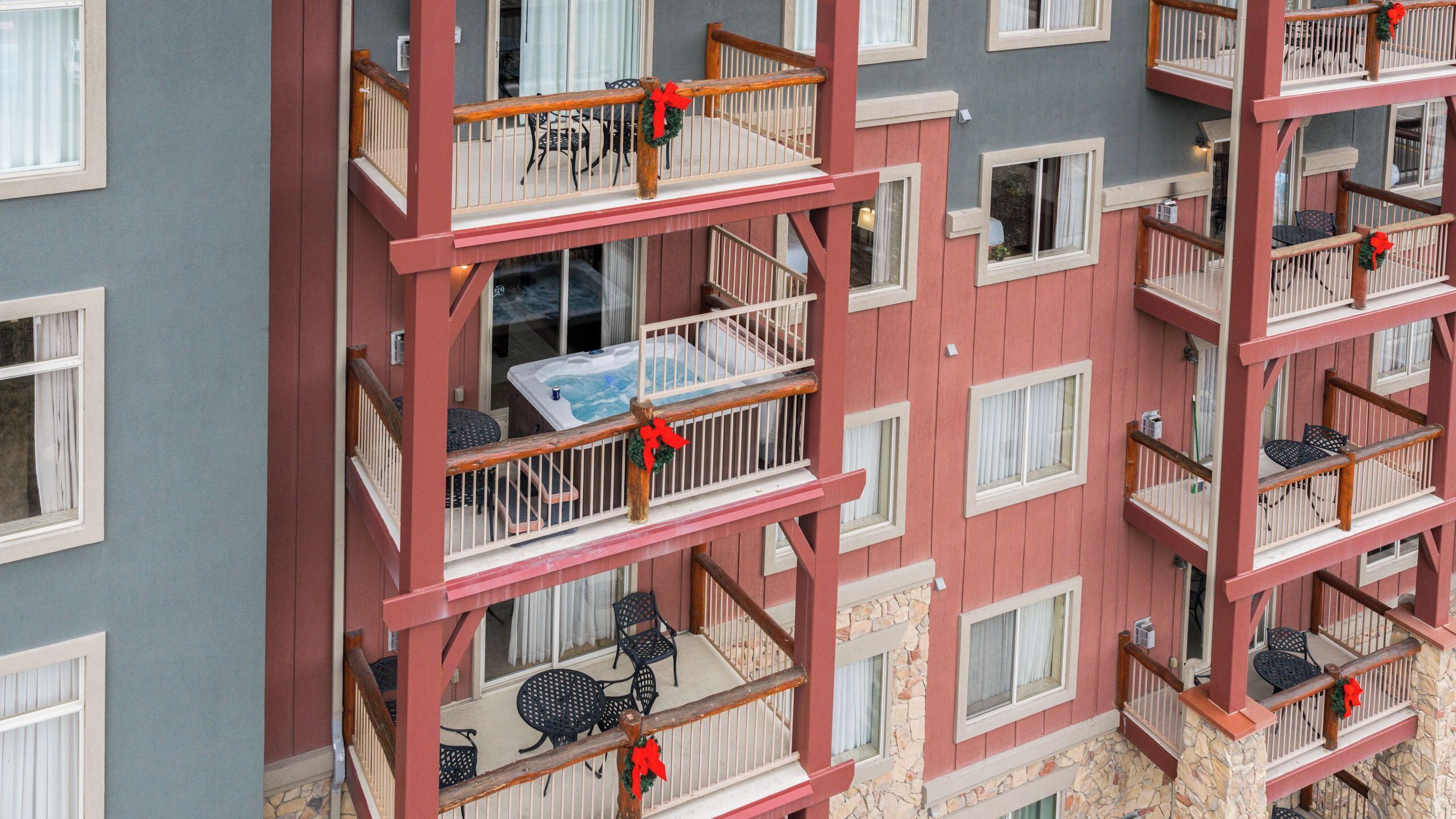 A multi-story building with balconies, each with a small table and chairs.