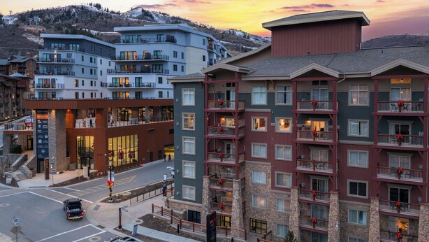 Un hôtel à plusieurs étages, doté de balcons, d’une façade en pierre et offrant une vue sur un paysage vallonné.