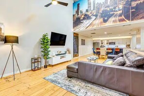 Ein modernes Wohnzimmer mit einer Couch, einem Fernseher, einer Pflanze und einer Stadtkulissen-Wandmalerei.