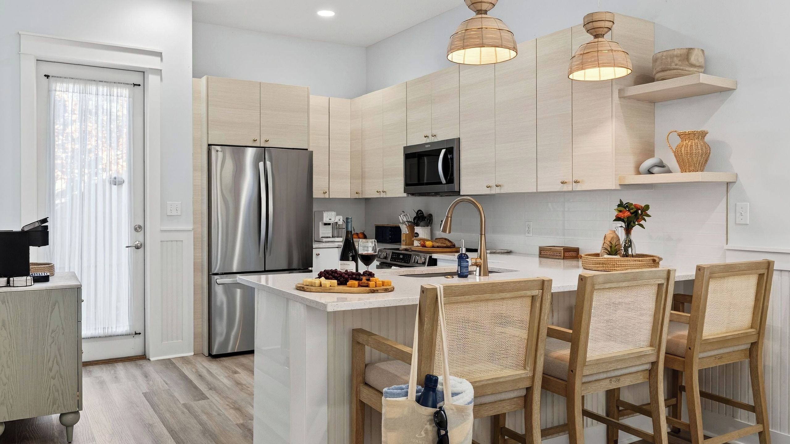A modern kitchen with a stainless steel refrigerator, a microwave, and a wooden island with seating.