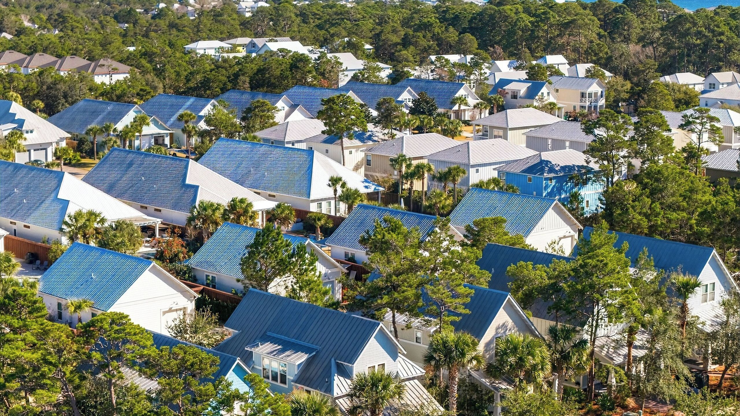 Un quartier résidentiel où les maisons se distinguent par leurs toits bleus et sont entourées d’arbres.