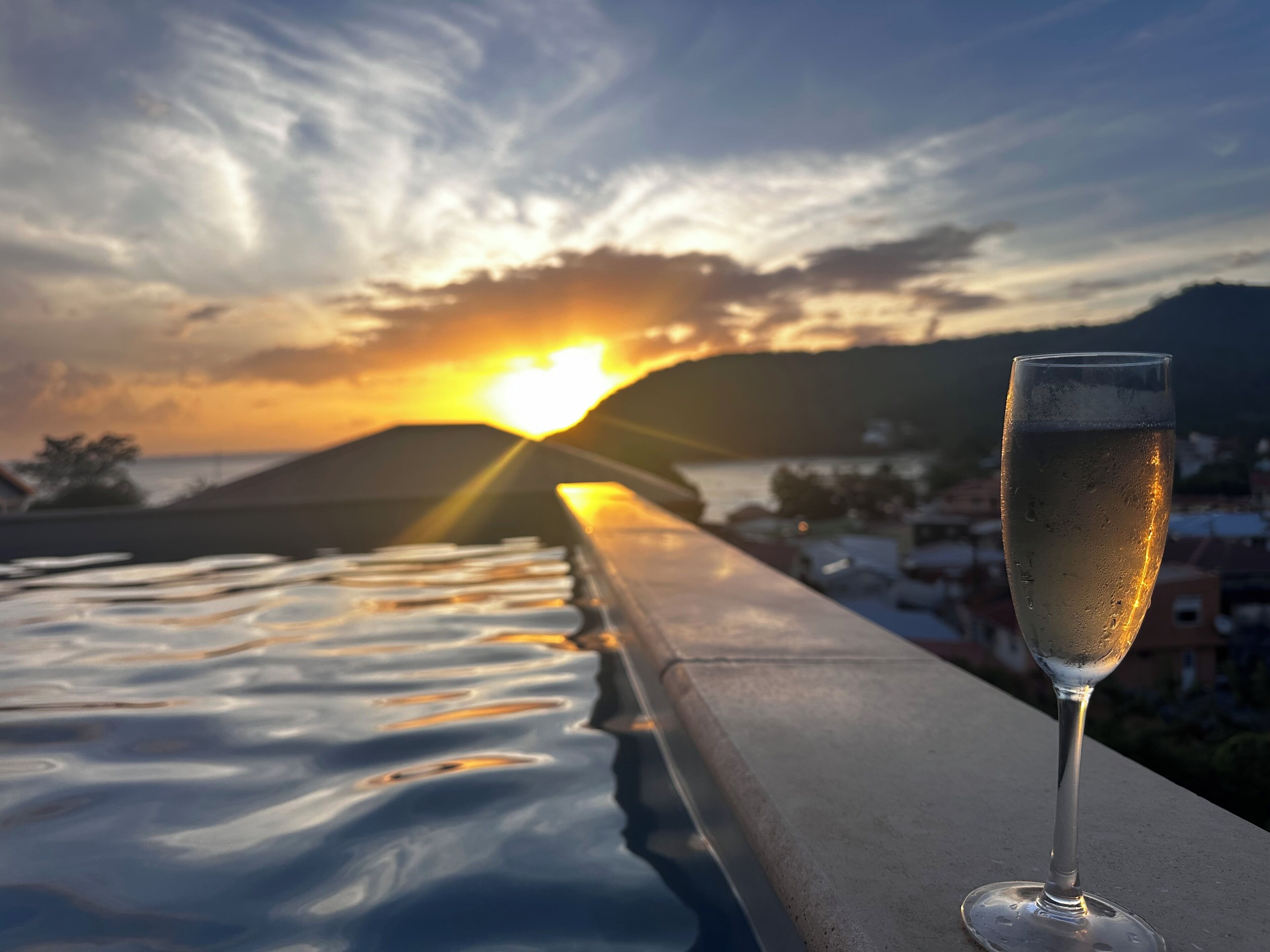A glass of champagne on a balcony with a sunset view.
