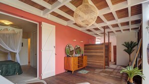 A room with a bed, a wooden cabinet, a hanging light fixture, and a potted plant.