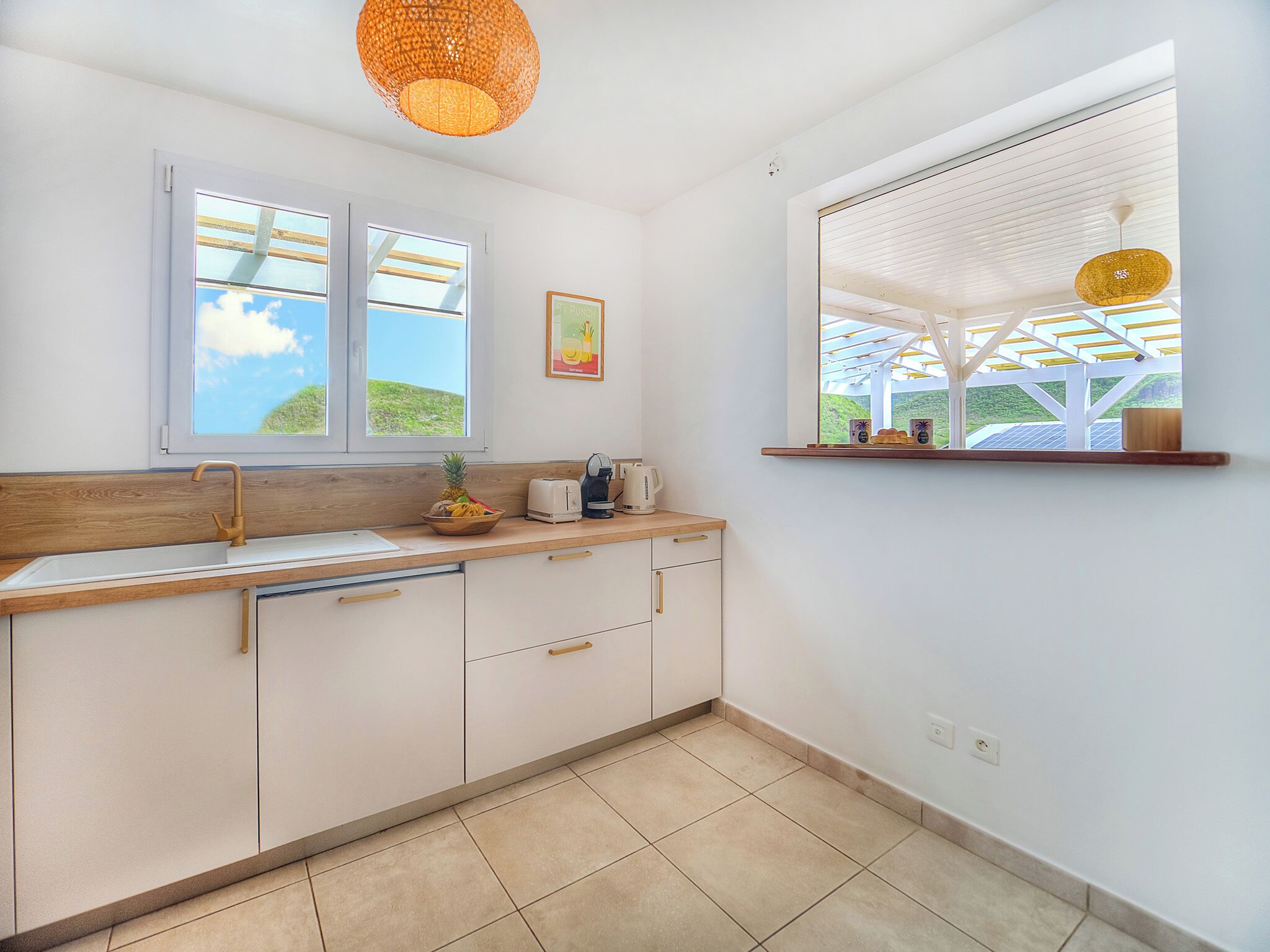 Una cocina con encimera de madera, armarios blancos, un lavamanos doble y una ventana con vistas a zonas verdes.