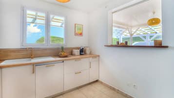 Una cocina con encimera de madera, armarios blancos, un lavamanos doble y una ventana con vistas a zonas verdes.