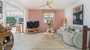 A living room with a TV, sofa, and a ceiling fan.
