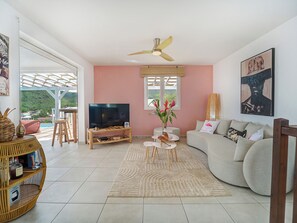 Un salon avec un téléviseur, un canapé et un ventilateur de plafond.