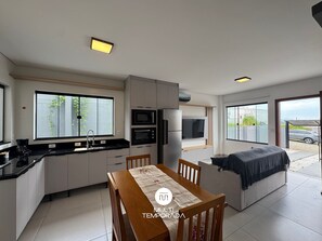 Une cuisine moderne dotée d’appareils électroménagers intégrés, un coin repas avec une table et des chaises, et un espace salon confortable avec un canapé.