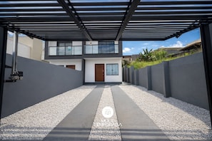 Una casa moderna de dos pisos con un camino cubierto y un sendero de grava.