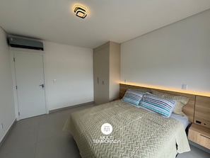 A bedroom with a bed, nightstands, a wardrobe, and a ceiling light fixture. - Sampaio's House - Gov. Celso Ramos - SC (Governador Celso Ramos)