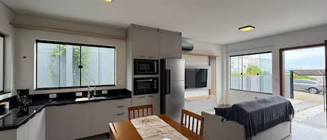 Una cocina moderna con electrodomésticos integrados, un comedor con mesa y sillas, y una zona de estar acogedora con sofá.