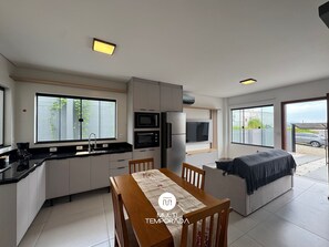 Una cocina moderna con electrodomésticos integrados, un comedor con mesa y sillas, y una zona de estar acogedora con sofá.