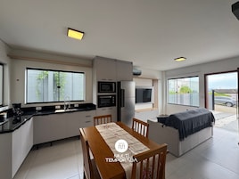 Una cocina moderna con electrodomésticos integrados, un comedor con mesa y sillas, y una zona de estar acogedora con sofá.