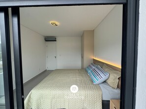 Un dormitorio con cama, mesita de noche, armario y luz en el techo.