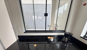 Una cocina con encimera negra, cafetera y dos recipientes etiquetados 'SAL' y 'AZÚCAR'.