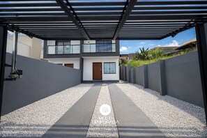 A modern two-story house with a covered driveway and a gravel pathway. - Sampaio's House - Gov. Celso Ramos - SC (Governador Celso Ramos)