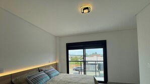 A bedroom with a bed, a window, and a ceiling light. - Sampaio's House - Gov. Celso Ramos - SC (Governador Celso Ramos)