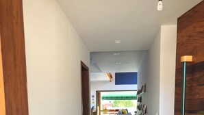 Ein Flur mit einer Holztür links, einer grünen Tür rechts und Blick in einen Wohnbereich mit Sofa und Esstisch.