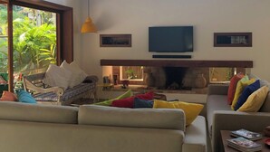 Ein modernes Wohnzimmer mit großem Fenster, Flachbildfernseher und Kamin.