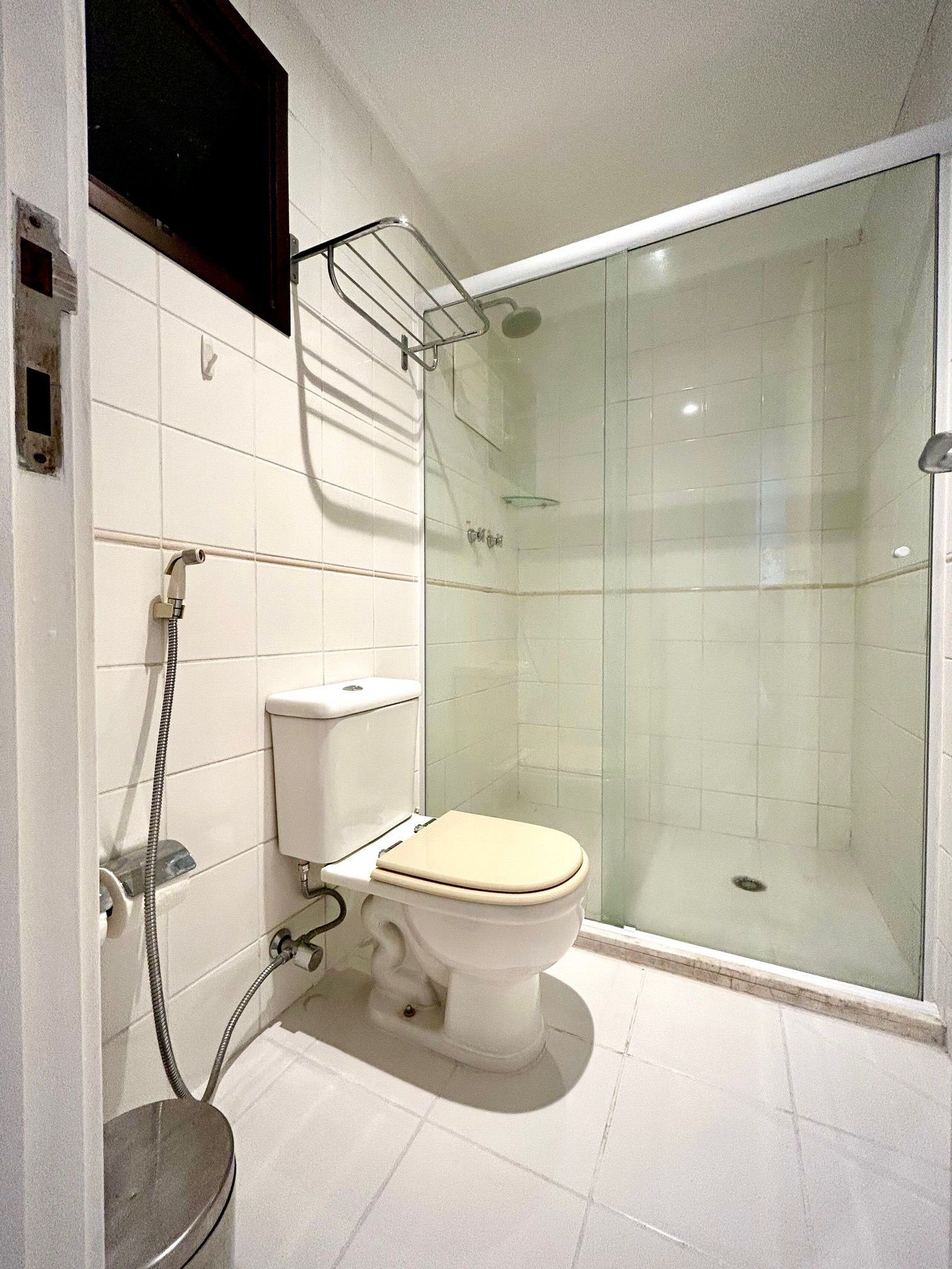 Un baño con inodoro, cabina de ducha y puerta de vidrio para la ducha.