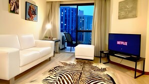 A modern living room with a white sofa, a zebra-patterned rug, a flat-screen TV displaying the Netflix logo, and a large window with a city view. - World Class Stay - Vila Olímpia (São Paulo)