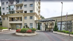 A multi-story hotel with a central courtyard, a covered entrance, and a flagpole. - World Class Stay - Vila Olímpia (São Paulo)
