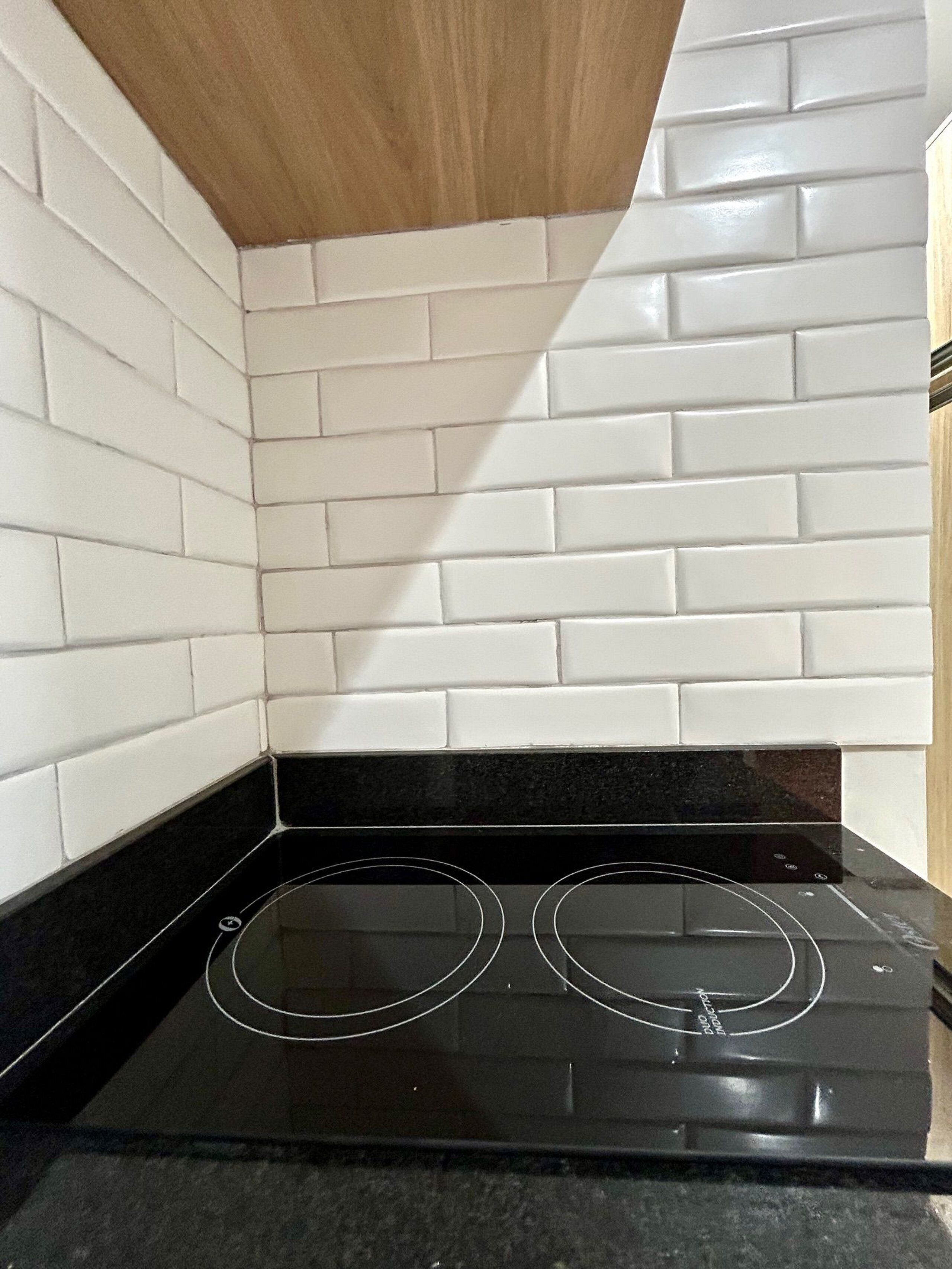 Una cocina con azulejos blancos tipo metro, una estufa negra y un techo de madera.