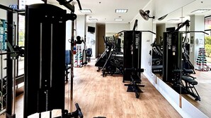A modern gym with various exercise equipment, a wooden floor, and large windows allowing natural light. - World Class Stay - Vila Olímpia (São Paulo)