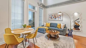 Een moderne woonkamer met een bank, gele stoelen, een salontafel en een grote spiegel.