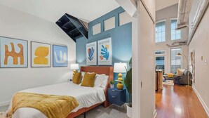 A modern bedroom with a bed, bedside tables, and artwork on the wall. - 2 Bed Midtown Loft Midtown (Atlanta)