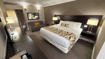 A hotel room with a large bed, a sofa, a desk, and a mirror.