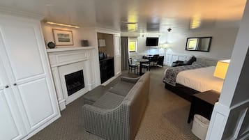 Une chambre d’hôtel équipée d’une cheminée, d’un canapé, d’un lit, d’un bureau et d’une télévision.