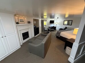 Una habitación de hotel con chimenea, sofá, cama, escritorio y televisor.