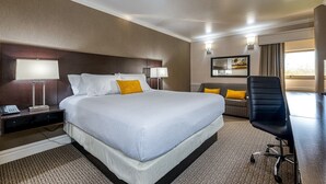 Une chambre d’hôtel avec un grand lit, un bureau avec un téléphone, une chaise et un canapé.