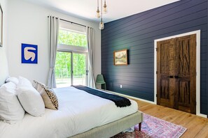Une chambre à coucher avec un lit, une fenêtre, une porte et un tableau accroché au mur.